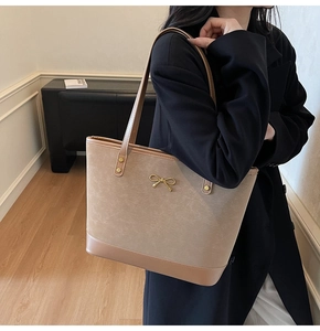 Detail of faux leather tote bag with gold bow clasp and reinforced rivet straps