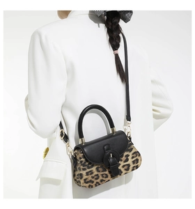Gros plan du sac bandoulière léopard avec rabat en cuir noir et boucle ronde dorée