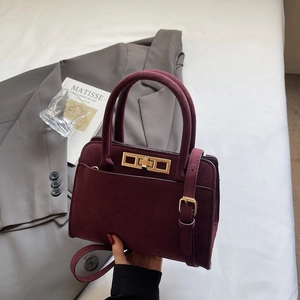 Vintage matte burgundy handbag with gold buckle and top handle shown in lifestyle setting
