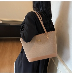 Close-up of khaki tote bag featuring a gold bow hardware and matte leather texture