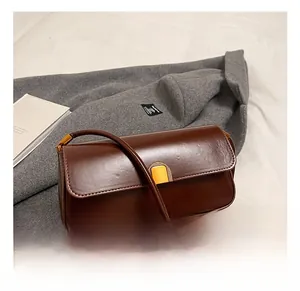 Close-up of brown rectangular shoulder bag with golden magnetic buckle on wool coat