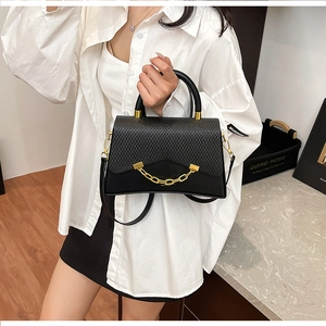 Détail du sac à main noir avec rabat tressé et grosse chaîne en métal doré brillante