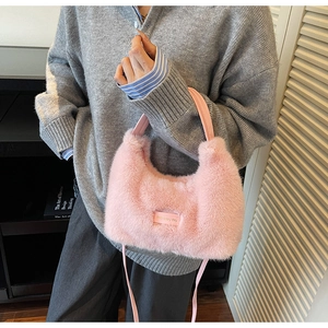 Detail of pink faux fur crossbody bag with love every day tag on a grey sweater