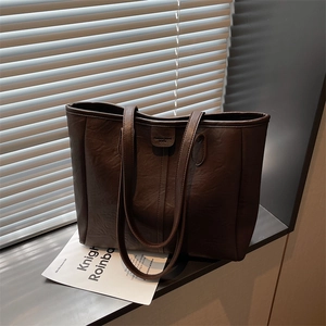 Borsa tote retrò marrone scuro in pelle con doppi spallacci in luce naturale dalla finestra