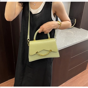 Détail du sac bandoulière vert citron avec rabat tressé et accents de chaîne dorée