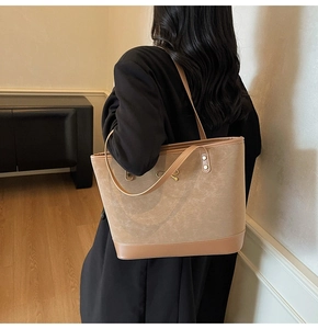 Detail of khaki leather tote bag with gold bow metal buckle shown on model shoulder
