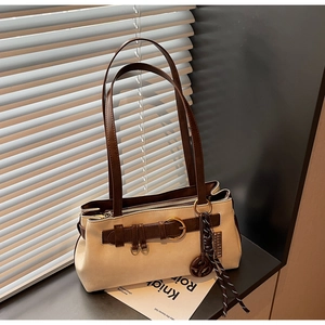 Detail of Boston bag featuring beige suede, brown leather straps and metallic buckle accent