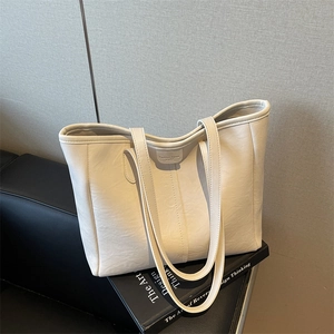 Elegante borsa tote in pelle beige con trama litchi su un libro di design per il pendolarismo