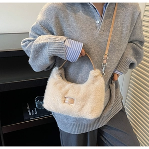 Detail of beige plush crossbody bag featuring brown leather tag and silver hardware