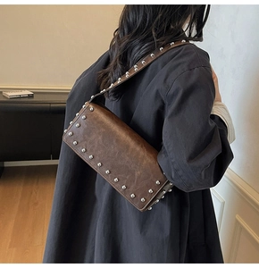 Detail of brown vintage shoulder bag with silver rivet studs and matte leather texture