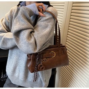 Detailed close-up of dark brown leather shoulder bag featuring vintage gold ring buckle