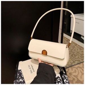Detail of a minimalist cream white leather underarm bag with a golden metal buckle