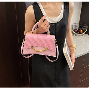 Détail du sac bandoulière rose avec rabat tressé et décoration de chaîne dorée chic