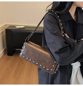 Detail of vintage brown shoulder bag with silver rivets and distressed leather texture