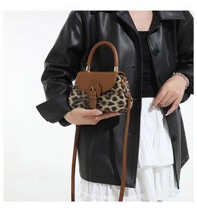 Détail du sac bandoulière léopard avec poignée en cuir marron porté par un mannequin