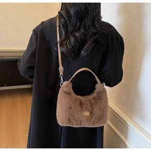 Detailed shot of brown faux fur crescent bag on a black wool coat, showing soft texture