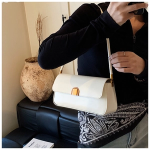 Close-up of a white patent leather shoulder bag with a rectangular gold metallic clasp