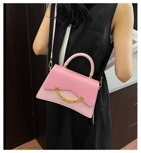 Détail d'un sac rose tendance avec texture tissée et chaîne dorée porté en bandoulière