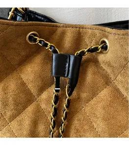 Macro view of brown suede bucket bag with diamond quilting and gold chain drawstring