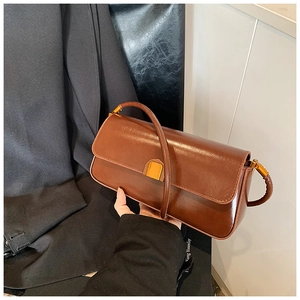 Detailed close-up of brown glossy leather bag with gold square buckle and strap
