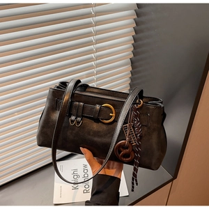 Detail of dark brown leather Boston bag with metallic ring and decorative woven knot charm