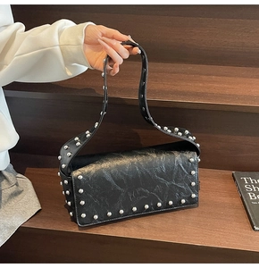 Close-up of black rivet pillow bag featuring oil wax leather texture and silver studs