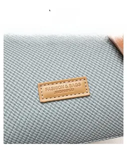 Macro shot of grey fabric texture and premium leather logo label on a modern handbag