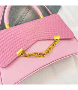 Détail du sac à main rose avec rabat à texture tissée et bandoulière chaîne dorée