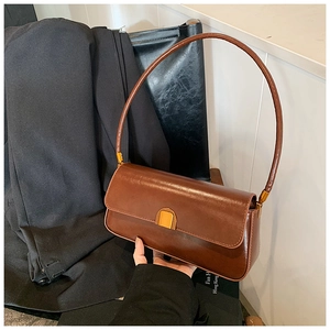Detail of a vintage dark brown baguette bag with smooth finish and gold metal buckle