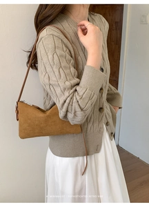 Sac baguette en daim marron porté avec un pull en maille beige et une jupe plissée