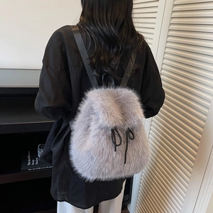 Detail of grey faux fur backpack showing dense texture and sleek black shoulder straps