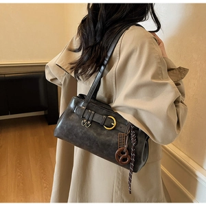 Detail of vintage brown leather underarm bag with bronze buckle and wooden charm accessory