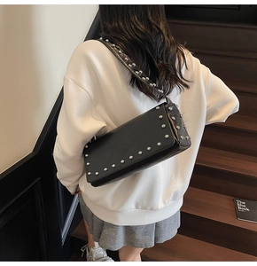 Detail of black leather underarm bag with silver rivet studs worn by a model