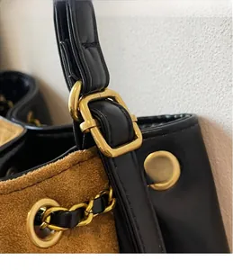 Macro shot of gold-tone metal hardware and mixed leather textures on a bucket bag