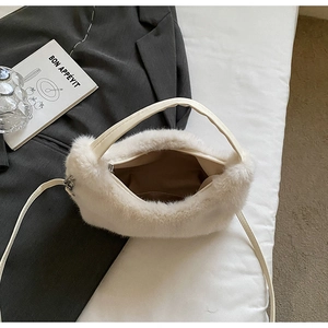 Overhead view of a fluffy cream plush crossbody bag on a grey suit jacket background