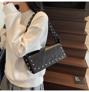 Detail shot of black rectangular shoulder bag with silver studs and wrinkled texture