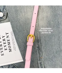 Gros plan détaillé de la bandoulière réglable rose avec boucle dorée sur jean