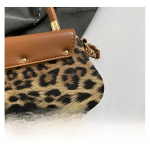Gros plan du sac bandoulière léopard montrant le cuir texturé et les rivets dorés