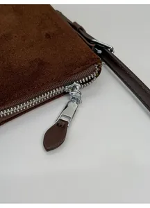 Détail du zip argenté et surpiqûres précises sur sac à bandoulière en daim marron