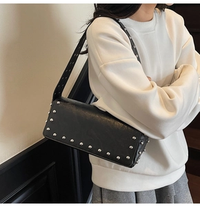 Detail of black faux leather shoulder bag with silver studs and textured finish