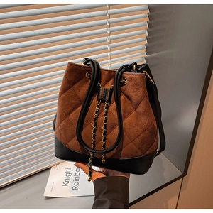Close-up of brown quilted suede bucket bag with black leather base and tassel detail