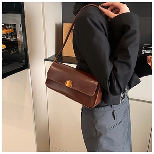 Detailed side view of a brown vintage leather baguette bag with a gold buckle clasp