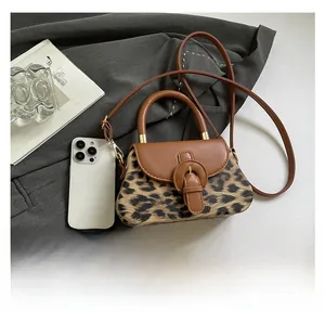 Détail d'un sac bandoulière léopard avec lanière en similicuir marron dans un décor chic