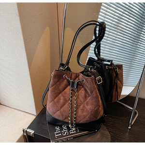 Detail of drawstring bucket bag showing brown quilted suede and black leather texture