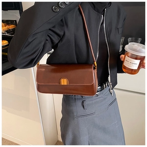 Detail of vintage dark brown leather baguette bag with a gold semi-circle buckle clasp