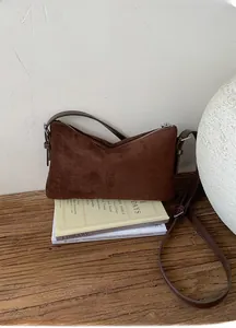 Gros plan d'un sac à main en cuir mat marron foncé avec fermeture éclair argentée