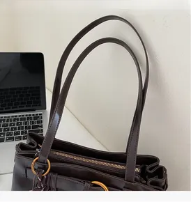 Detail of dark brown leather tote bag with gold ring hardware and sturdy handle straps