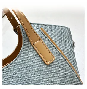 Macro view of woven light blue fabric with leather handle and reinforced stitching