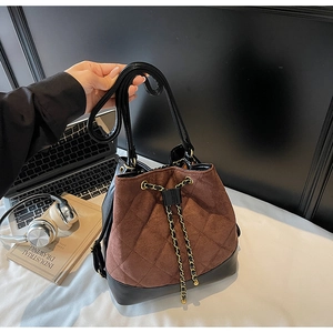 Detail of quilted brown suede bucket bag with black base and golden chain drawstring