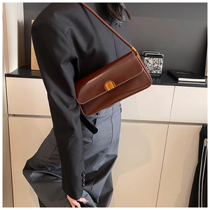Detail of vintage brown leather underarm bag featuring a golden rectangular clasp
